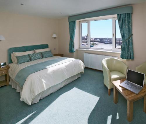 a bedroom with a bed and a laptop on a table at The Ship Inn in Stonehaven