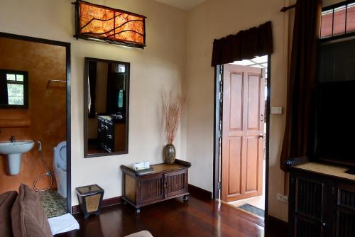 a living room with a table and a mirror at Banjai Garden Guesthouse in Chiang Mai