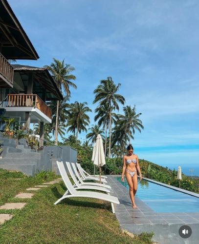 a woman in a bikini walking towards a pool at a resort at Bintana sa Paraiso Binunsaran in Mambajao