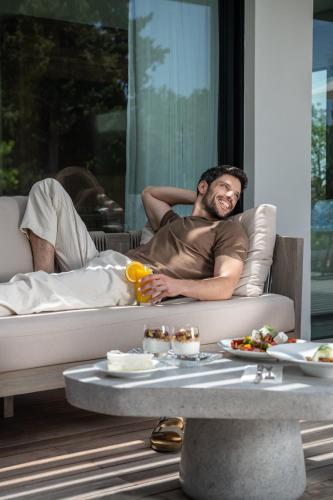 a man laying on a couch with a drink at Carmel Forest by Isrotel Exclusive in Bet Oren