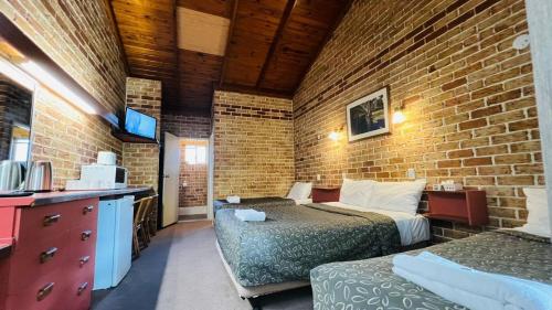 a room with two beds and a brick wall at Beenleigh Village Motel in Beenleigh