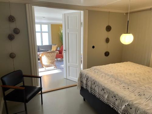 a bedroom with a bed and a chair and a door at 1. etg i Dampskipsbrygga, Lødingen havn in Lødingen