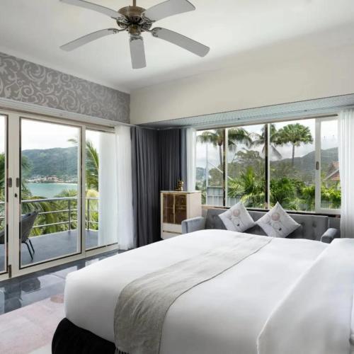 a bedroom with a large white bed and large windows at Vipa Seaview Villa in Patong Beach