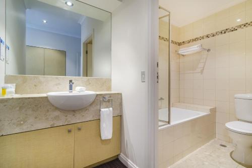 a bathroom with a sink and a toilet and a tub at Clarion Suites Gateway in Melbourne