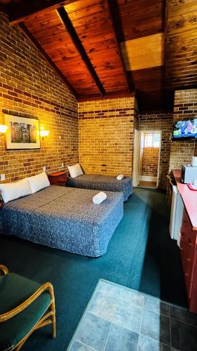 a room with two beds and a brick wall at Beenleigh Village Motel in Beenleigh