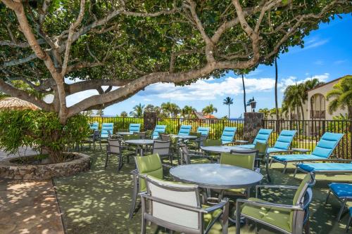 a group of tables and chairs under a tree at Aston Maui Hill in Wailea