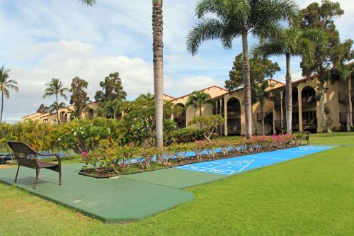 a bench in front of a resort with palm trees at Aston Maui Hill in Wailea
