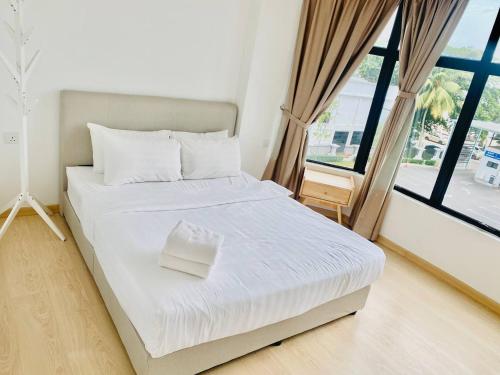 a white bed in a room with a large window at Mutiara Melaka Beach Resort by Glex in Tangga Batu