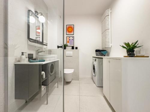 a bathroom with a sink and a washing machine at Klimeckiego Luxury Apartments 215 in Kraków