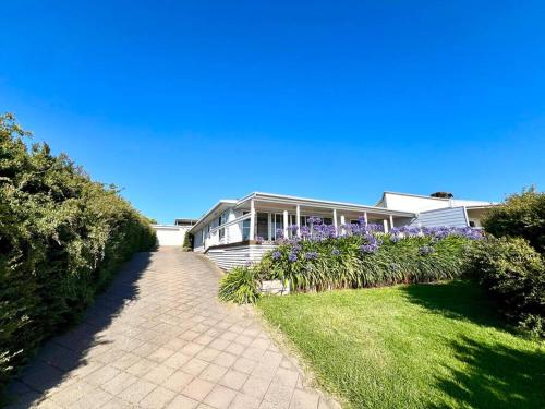 a house with purple flowers in front of a driveway at Cactus- Spectacular Views On The Ocean Front Pet friendly in Emu Bay