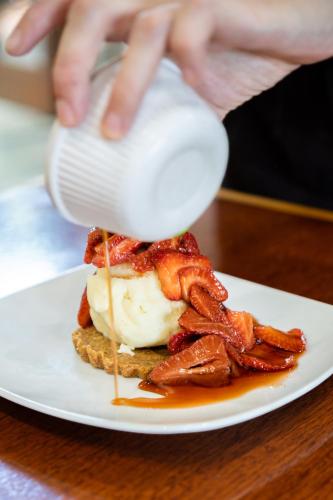 a person pouring sauce on a sandwich on a plate at Peel Inn Hotel Nundle in Nundle