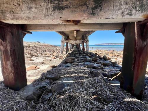 a bridge on a beach with rocks under it at Cactus- Spectacular Views On The Ocean Front Pet friendly in Emu Bay