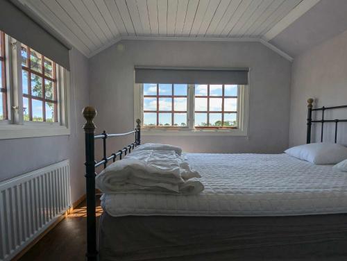 a bed in a room with two windows at Gunnabo in Borgholm