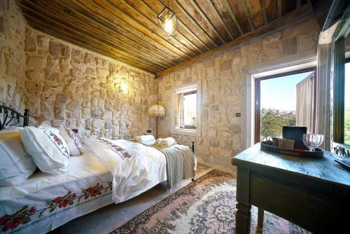 a bedroom with a bed and a stone wall at Aysel Inn House in Goreme