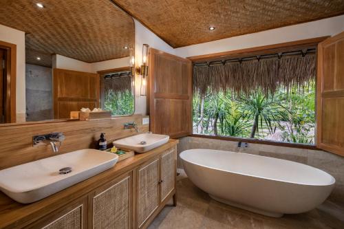 a bathroom with two sinks and a tub and a window at The Mesare Eco Resort in Nusa Penida