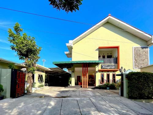 a yellow building with a driveway in front of it at Wisma Anugerah Redpartner Near Masjid Zayed Solo in Bonorejo