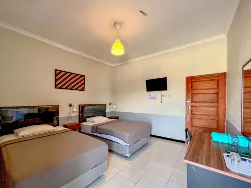 a hotel room with two beds and a tv at Wisma Anugerah Redpartner Near Masjid Zayed Solo in Bonorejo
