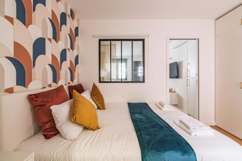 une chambre avec un grand lit avec des oreillers colorés dans l'établissement MM Suites Saint-Remi, à Reims