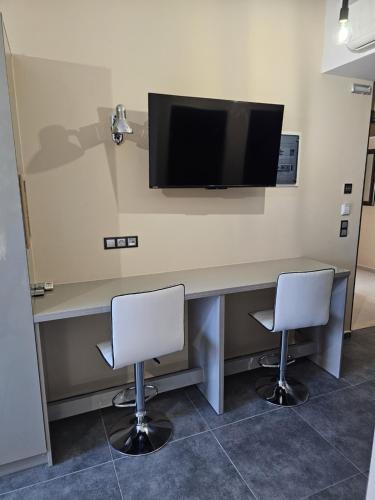 a desk with two chairs and a television on a wall at The Santo George Beach Resort in Amoudara Herakliou
