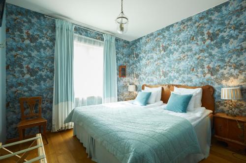 a bedroom with a bed with blue floral wallpaper at Pariisin Ville in Porvoo