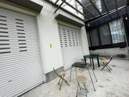 three chairs and a table in front of a garage at SADO Stay03 広々一軒家 貸し切り古民家ステイ バーベキュー可 10人までOK in Sado