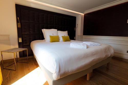 a bedroom with a large white bed with yellow pillows at Hôtel Merveilleux Côté Mer in Dunkerque