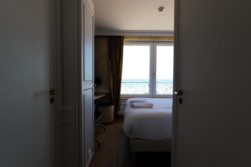 a bedroom with a bed and a view of the ocean at Hôtel Merveilleux Côté Mer in Dunkerque