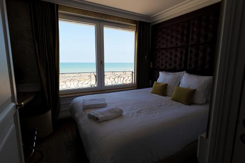 a bedroom with a large bed with a large window at Hôtel Merveilleux Côté Mer in Dunkerque