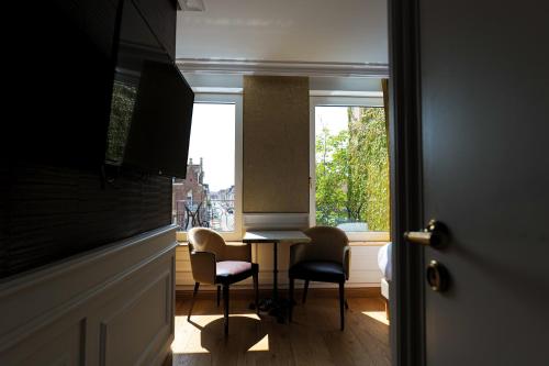 a room with a table and chairs and a window at Hôtel Merveilleux Côté Mer in Dunkerque