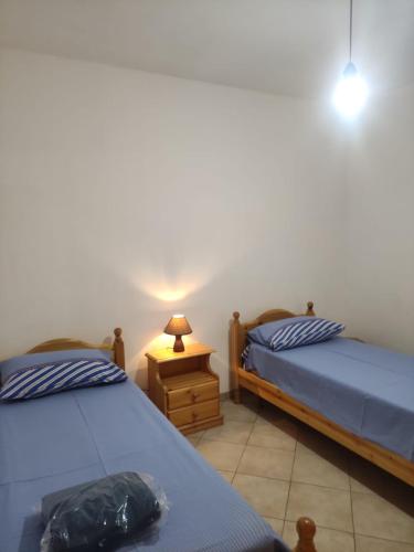 a bedroom with two beds and a table with a lamp at Casa vacanza Tanja Leuca in Leuca