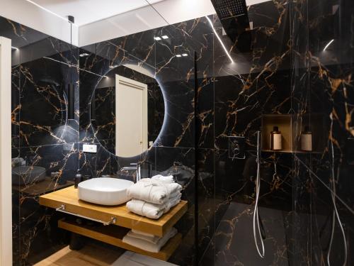 ein Bad mit schwarzen Marmorwänden und einem Spiegel in der Unterkunft Regola Luxury Relais in Rom