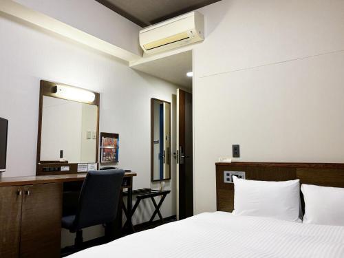 a bedroom with a bed and a desk and a mirror at Hotel Route-Inn Seki in Sekimachi