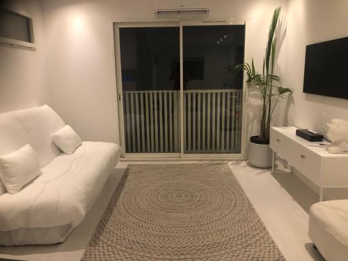 un salon avec un canapé blanc et une télévision dans l'établissement Logement au calme, à Montpellier