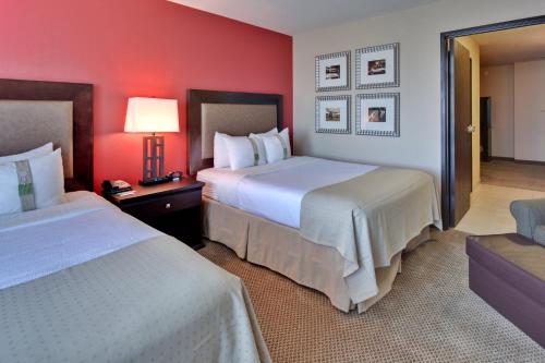 two beds in a hotel room with red walls at Holiday Inn & Suites Bakersfield by IHG in Bakersfield