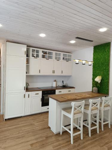 a kitchen with white cabinets and a table and chairs at Pievų Tako kiemelis in Klaipėda