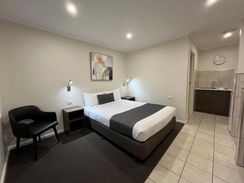 a hotel room with a bed and a chair at Ryley Motor Inn in Wangaratta