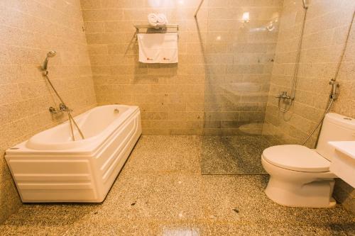 a bathroom with a tub and a toilet and a sink at Mai Vy Hotel Trảng Bàng in Trảng Bàng