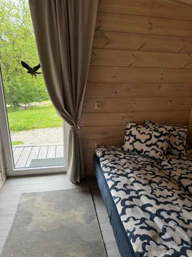 a bedroom with a bed and a large window at Obuoliu Sala COZY HOUSE on the Apple Island in Gaylyunay