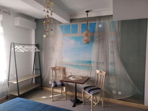 a bedroom with a table and two chairs and a bed at CHAMBRES DE L'ORATOIRE-climatisées, Impasse calme, lumineuse, centre ville, Pézenas in Pézenas