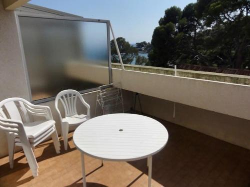 un balcon avec des chaises blanches et une table et une table blanche et des chaises dans l'établissement Saint-Raphaël Le Salus, à Saint-Raphaël
