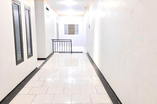 a hallway with white walls and a tile floor at Urbanview The Halona near Jawa Timur Park 4 in Batu