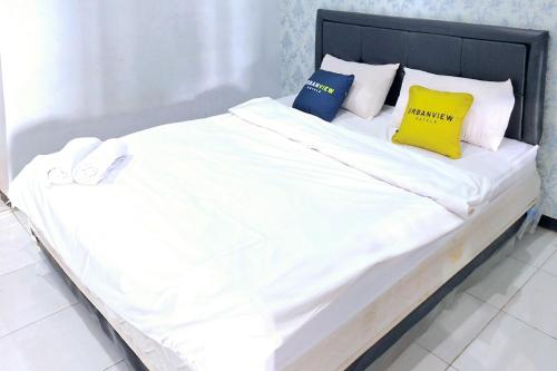 a large bed with white sheets and yellow pillows at Urbanview The Halona near Jawa Timur Park 4 in Batu