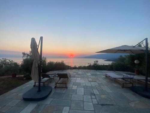 a patio with an umbrella and chairs and a sunset at Villa Wishflower in Lefokastro