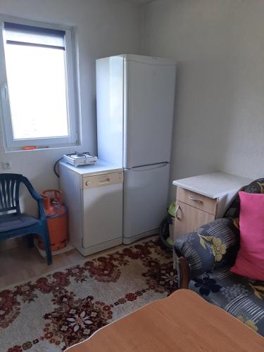a kitchen with a refrigerator and a chair and a window at Gorazde vikendica in Goražde
