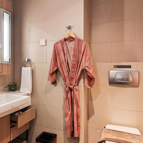 a robe hanging on a wall in a bathroom at Ra Premiere Simatupang in Jakarta