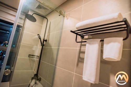 a bathroom with a shower and towels on a wall at Hotel Serviced Condo Unique Infinity Pool with Mekong River View in Phnom Penh