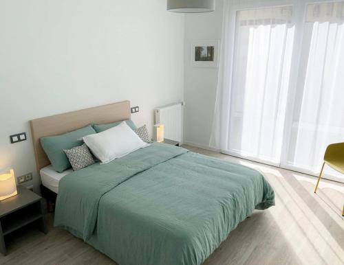 a bedroom with a large bed with a green blanket at Oh Activ Les Ponts-de-Cé in Les Ponts-de-Cé