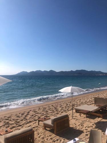 - une plage avec des chaises, un parasol et l'océan dans l'établissement Magnifique vue mer, grande terrasse et piscine, à Cannes