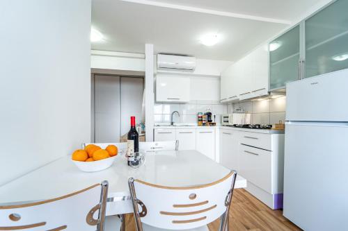 a white kitchen with a table with a bowl of oranges at El Reino Azul de Gran Canaria in Melenara