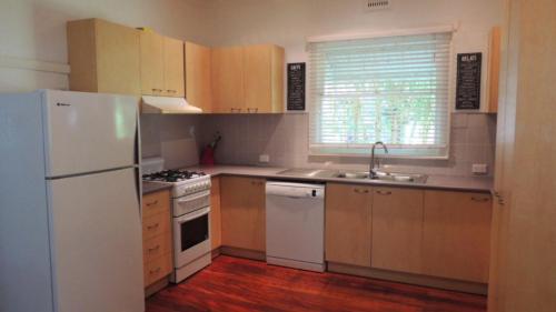 a kitchen with wooden cabinets and a white refrigerator at Brunswick Heads - Fingal Street in Brunswick Heads